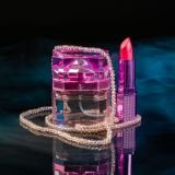 Perfume with bead necklace and red lipstick. Vertical shot black background.