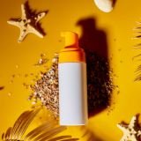 Top view, flat lay Sunscreen tube mockup with shells, sand yellow background, summer vacations and spf uv-protecting skin care concept, hard light.